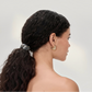 Woman with styled hair and earrings on a plain background